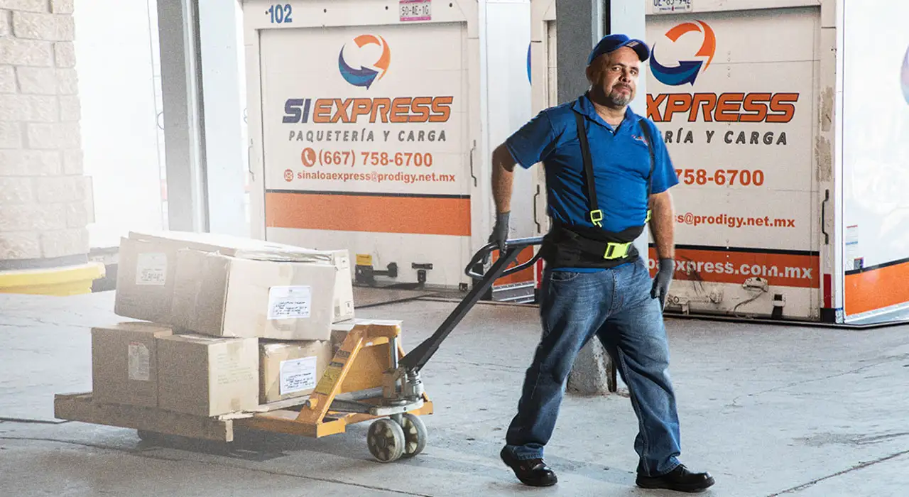 Personal de SiExpress moviendo tarima con patín hidráulico frente a unidades rotuladas